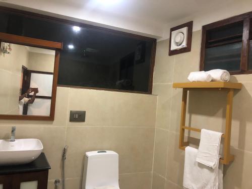 a bathroom with a toilet and a sink and a mirror at Anitha's Garden Stay in Kovalam