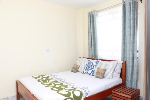 a small bedroom with a bed and a window at Zanale Stays Furnished Apartment? in Nairobi