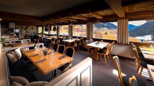 a restaurant with tables and chairs with mountains in the background at Cresta Sedrun in Sedrun