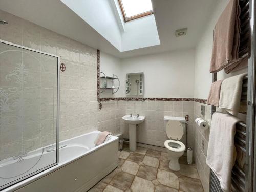 a bathroom with a tub and a toilet and a sink at The Waterings in St. Davids