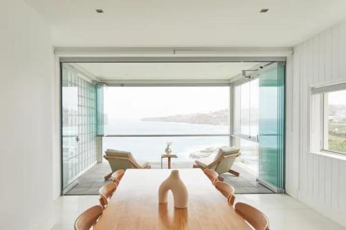 雪梨的住宿－Oceanfront Tamarama Apartment: Best View in Sydney，一间带桌子和大窗户的用餐室