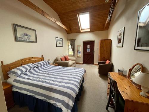 a bedroom with a bed with a blue and white striped blanket at The Waterings in St. Davids