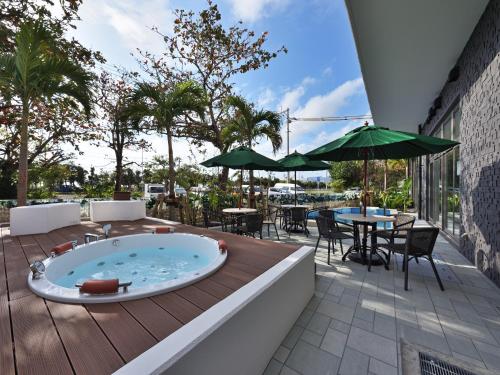 a hot tub on a deck with a table and chairs at Green Rich Hotel Okinawa Nago (Artificial hot spring Futamata Yunohana) in Nago