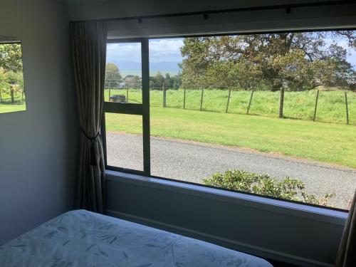 a bedroom with a window with a view of a field at Kaiaua Bayview Farm Apartment in Auckland