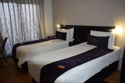 two beds in a hotel room with white sheets at Scenery Maqalika Guesthouse in Maseru