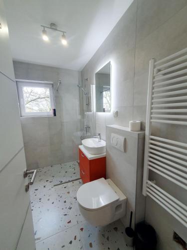 a bathroom with a white toilet and a sink at StudioApartman M in Valpovo