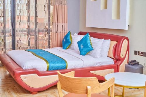 a red bed in a room with a table at Wilsen Hotel Nansana in Kampala