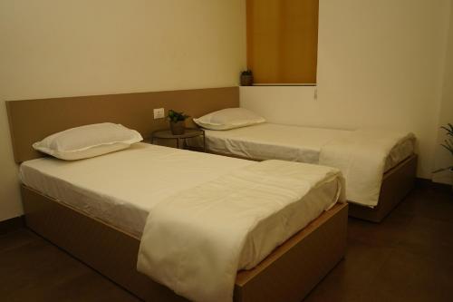 two beds in a hotel room with twothirdsessions at DayOne Suites Kuvempu in Bangalore