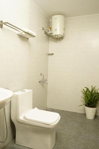 a white bathroom with a toilet and a sink at DayOne Suites Kuvempu in Bangalore