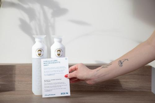 a person holding a bottle of hand sanitizer next to a bottle of soap at Bob W Sentralen in Oslo