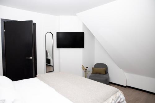 a white bedroom with a bed and a chair at Bob W Sentralen in Oslo