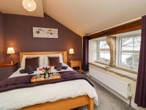 a bedroom with a large bed with a tray of flowers on it at Mirk Cottage in Hebden Bridge