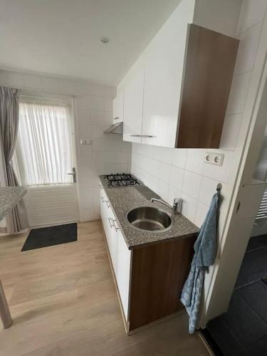 a small kitchen with a sink and a stove at Have a nice stay! - Zomerhuis Toda Cambia dicht bij strand in Noordwijk aan Zee