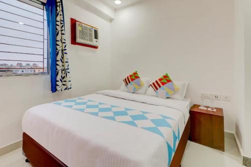 OYO Flagship Delightful Stay Em Byepass Near Birla Mandir في Tangra: غرفة نوم بيضاء بها سرير ونافذة