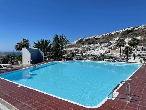 une grande piscine avec une montagne en arrière-plan dans l'établissement Guayana 23 beach apartment, à Mogán