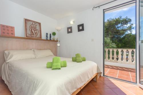 Un dormitorio con una cama con almohadas verdes. en Arbocers en Ciutadella
