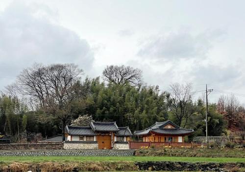 a chinese house in a field with trees in the background at Hanok Stay - JukRokJungSa in Gurye