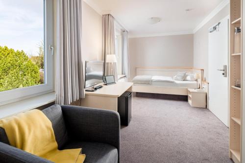 ビューズムにあるAkzent Hotel Dornのベッド、ソファ、テレビが備わるホテルルームです。