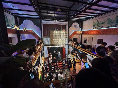 a group of people sitting in a room with a crowd at Photohostel in Bangkok