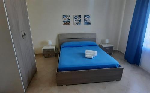 ein Schlafzimmer mit einem blauen Bett und zwei Nachttischen in der Unterkunft Casa vacanze Tommasone in Custonaci