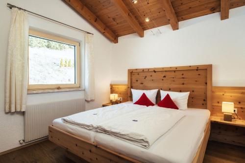a bedroom with a large white bed with red pillows at Apart Piz Lad in Nauders