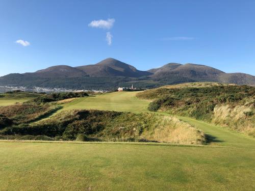 a view of a golf course with mountains in the background at Rocklea Seaside Cottage in Newcastle