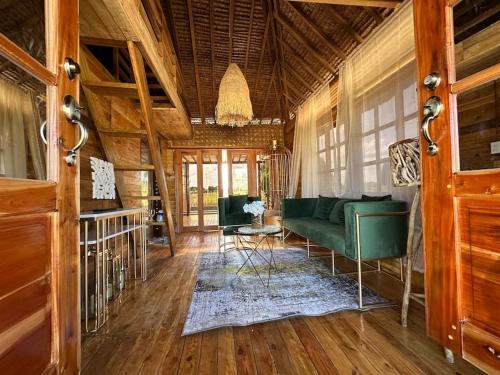a living room with a green couch and wooden floors at Rancho Oco Pinewood Villa with Swimming Pool in Nasugbu