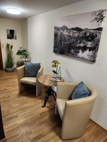 a waiting room with chairs and a table and a painting at Hotel & Restaurant Sonnenhöfle in Sommerhausen