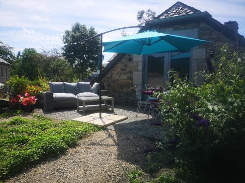 a patio with a couch and an umbrella at Le Buron des Loups in Soulages-Bonneval
