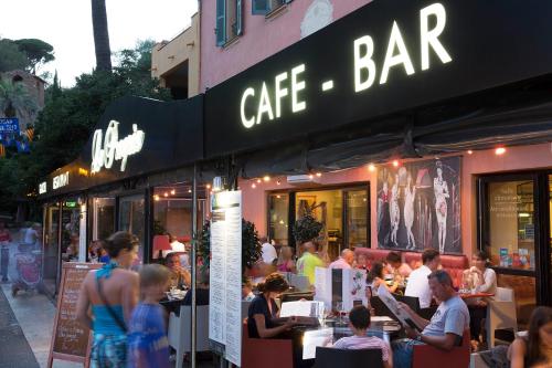 un groupe de personnes assises à des tables à l'extérieur d'un café-bar dans l'établissement Hostellerie du Cigalou - Les Collectionneurs, à Bormes-les-Mimosas