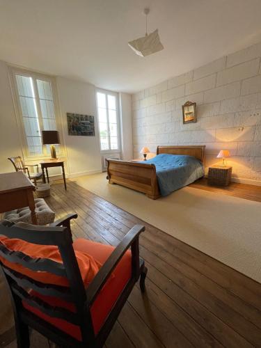 une chambre avec un lit et une chaise dans une pièce dans l'établissement La Maison du Port, à Mortagne-sur-Gironde