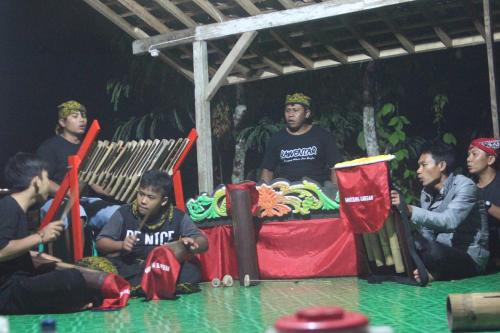 a group of men sitting on a stage in a room at Agus Hidden Homestay - Banjar Sweet Village-Ijen in Banyuwangi
