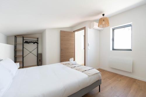 une chambre blanche avec un grand lit et une fenêtre dans l'établissement La Maison du Parc 2 - Parking Clim, à Marseille
