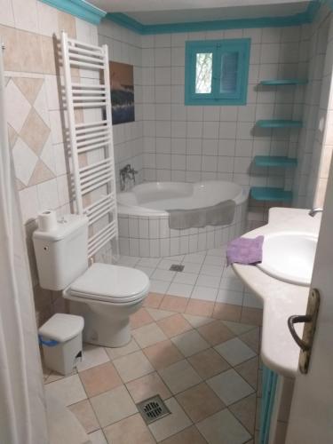 a bathroom with a toilet and a sink and a tub at VILLA KANTOUNI ON THE BEACH in Panormos Kalymnos