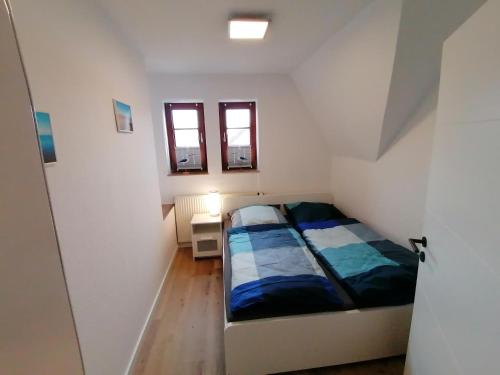 a small bedroom with a bed and two windows at Dünenrose in Horumersiel