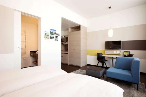 a bedroom with a bed and a desk and a chair at Vienna House Easy by Wyndham Osnabrück City & Apartments in Osnabrück