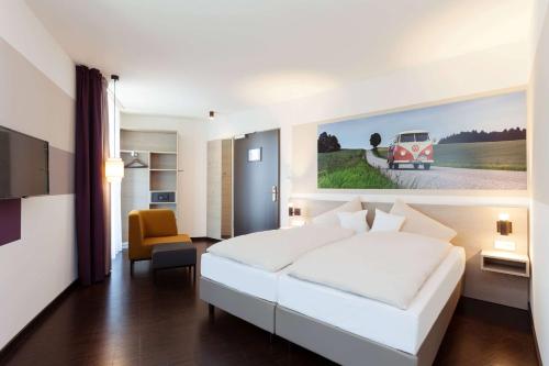 a bedroom with a white bed and a painting of a car at Vienna House Easy by Wyndham Osnabrück City & Apartments in Osnabrück