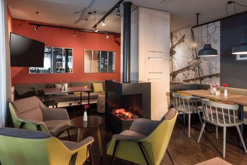Un restaurante con chimenea, mesas y sillas. en Vienna House Easy by Wyndham Bremen City Apartments, en Bremen
