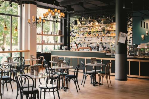 a restaurant with tables and chairs in front of a counter at Vienna House Easy by Wyndham Leipzig in Leipzig