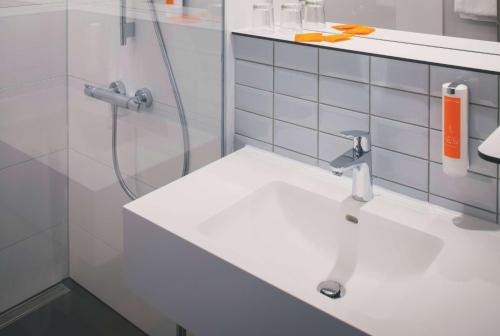 a bathroom with a sink and a shower at Vienna House Easy by Wyndham Leipzig in Leipzig