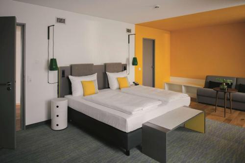 a bedroom with a large bed and a couch at Vienna House Easy by Wyndham Leipzig in Leipzig