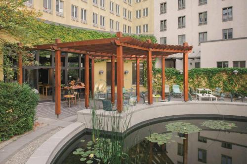 a pergola over a pond in front of a building at Vienna House Easy by Wyndham Leipzig in Leipzig