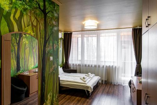 1 dormitorio con 1 cama y un mural de árboles en Ózoon Hotel, en Nyíregyháza