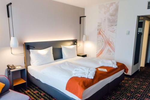 a hotel room with a bed with towels on it at Vienna House Easy by Wyndham Bucharest Airport in Otopeni
