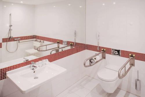 a bathroom with a white toilet and a sink at Vienna House Easy by Wyndham Bucharest Airport in Otopeni