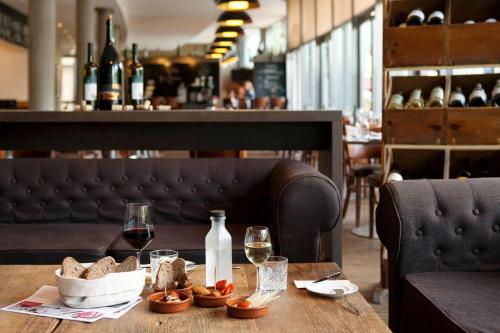 a wooden table with glasses of wine and bread on it at Vienna House by Wyndham Havelufer Potsdam in Potsdam