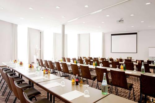a conference room with tables and chairs and a projection screen at Vienna House by Wyndham Havelufer Potsdam in Potsdam