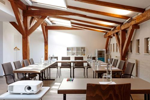 a dining room with tables and chairs and wooden beams at Vienna House by Wyndham Havelufer Potsdam in Potsdam