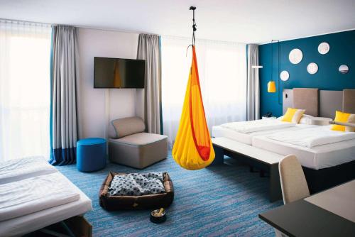 a hotel room with two beds and a hammock at Vienna House Easy by Wyndham Günzburg in Günzburg