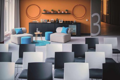 a room with white chairs and blue chairs at Vienna House Easy by Wyndham Landsberg in Landsberg am Lech
